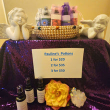 Load image into Gallery viewer, Table with 'Pauline's Potions' products, including bottles and a basket, with a sign indicating pricing.
